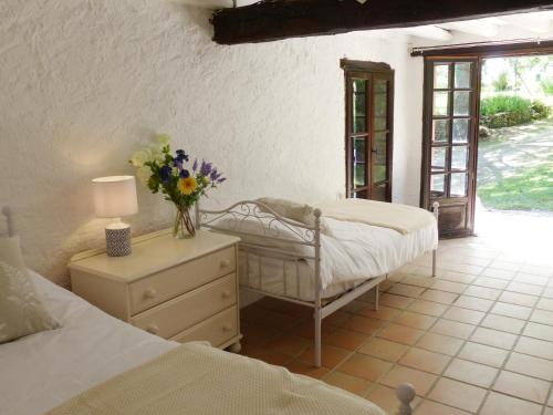 Hameau de Montcabirol - Foix في ماريبواه: غرفة نوم بسريرين وطاولة مع إناء من الزهور