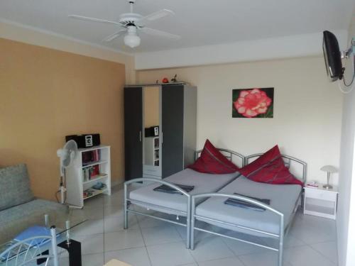a bedroom with a bed with red pillows and a couch at Studios Oleander in Limenaria