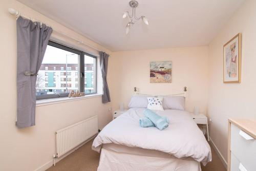 ein kleines Schlafzimmer mit einem Bett und einem Fenster in der Unterkunft Bright Contemporary Merchant City Flat in Central Location in Glasgow