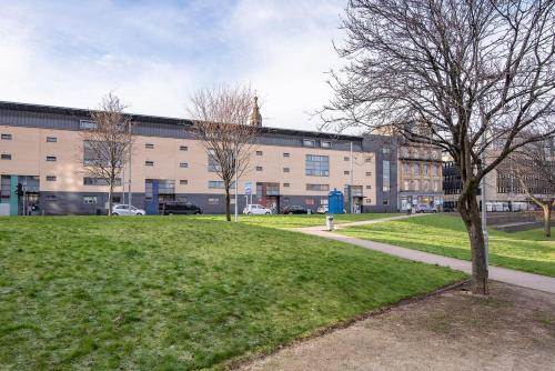 a park with a building and a tree and a sidewalk at The Socair - Bright Contemporary Merchant City Flat in Central Location in Glasgow