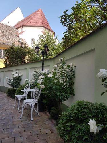 um pátio com duas cadeiras, uma mesa e flores em Maison Elysée em Sibiu