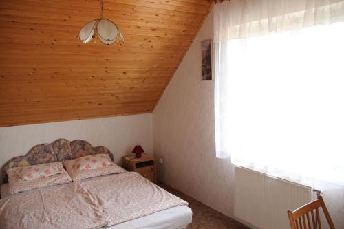 um quarto com uma cama com tecto em madeira e uma janela em Susanne Apartman em Balatonboglár
