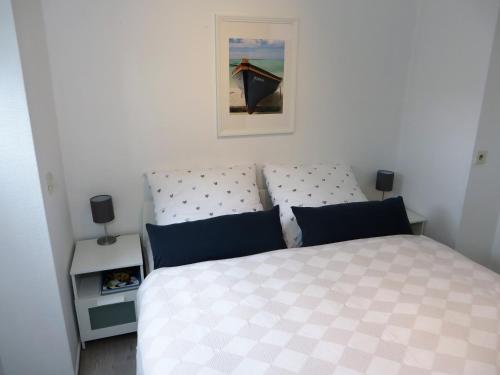 ein Schlafzimmer mit einem weißen Bett mit blauen Kissen in der Unterkunft Ferienwohnung Elbe Diek in Stelle