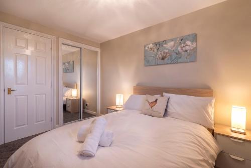 1 dormitorio con 1 cama blanca y 2 lámparas en SEC/ Hydro Two Bed Flat With Free parking and Great View en Glasgow