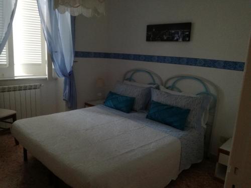 a bedroom with a white bed with blue pillows at Villetta Baia San Montano in Ischia