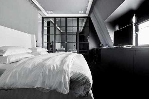 a bedroom with a bed and a desk with a television at Hotel Odette en Ville in Brussels