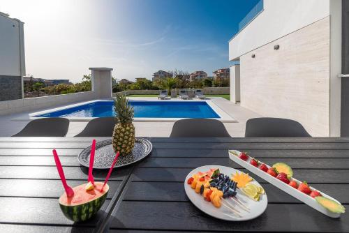 a table topped with plates of fruit and a pineapple at Apartments & Rooms Pool Villas Maris in Novalja