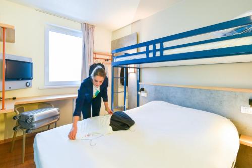 a young girl is making a bed in a room at ibis Budget Charleroi Airport in Charleroi