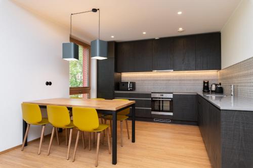 a kitchen with a wooden table and yellow chairs at Self-check-in 3 bedroom apartment with sauna and balconies in Tallinn