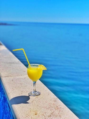 a glass of orange juice sitting next to a swimming pool at Apart Lux Beciragic in Dobra Voda