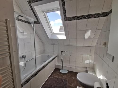 ノルデンハムにあるFerienwohnung bei Schwarzkopfのバスルーム(バスタブ、トイレ付)、窓が備わります。