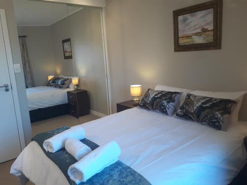 um quarto com uma grande cama branca e um espelho em Field's Rest: The Apartment em Port Elizabeth