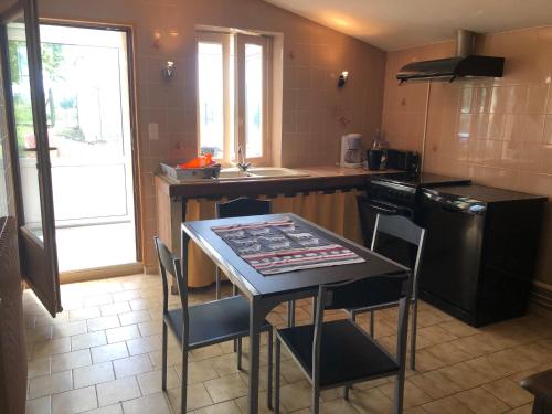 uma cozinha com uma mesa, cadeiras e um fogão em Chez Lysette em Mesnac
