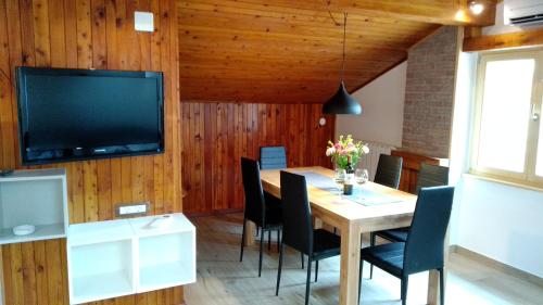 una sala da pranzo con tavolo, sedie e televisione di Hiša Kala a Kobarid