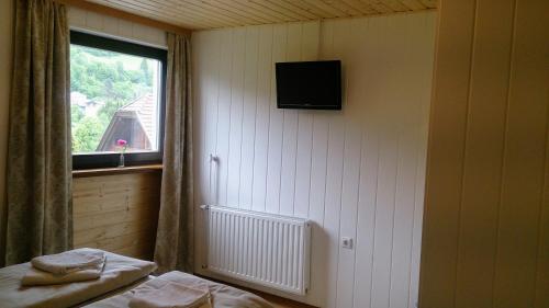 a room with a bed and a window and a television at Pension Julia in Feld am See
