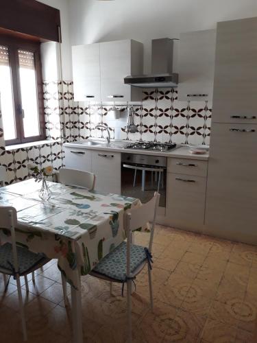 una cocina con mesa y sillas y una cocina con armarios blancos. en Casa MARINA, en Policastro Bussentino