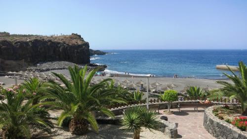 a beach with palm trees and umbrellas and the ocean at 100 meters from the ocean in Callao Salvaje