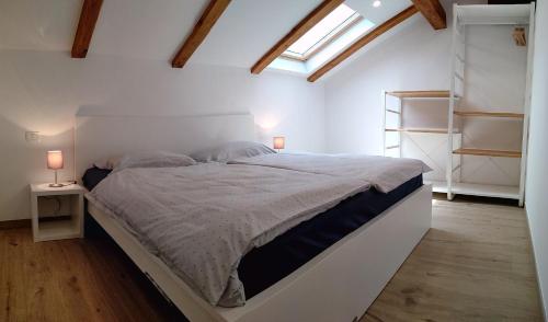 a white bedroom with a large bed with a window at Hiša Kala in Kobarid