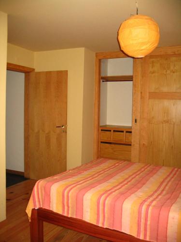 a bedroom with a bed with a striped blanket at Casa do Castanheiro in Outeiro