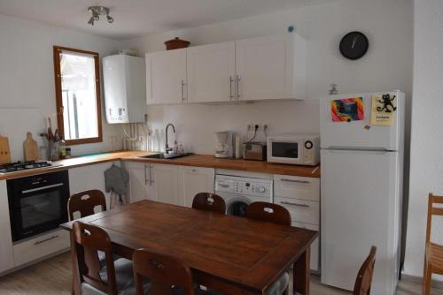 une cuisine avec une table et un réfrigérateur blanc dans l'établissement T3 3 étoiles hyper centre Luchon, à Luchon