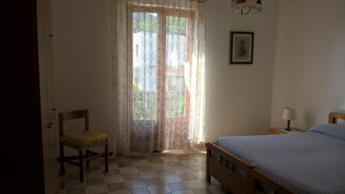 Un dormitorio con una cama y una silla y una ventana. en Casa Engy, en Lipari