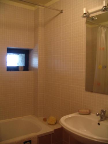 une salle de bains avec baignoire, lavabo et miroir dans l'établissement Casa do Castanheiro, à Outeiro