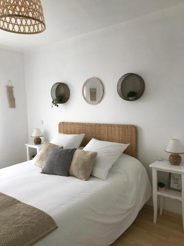 a bedroom with a white bed with two mirrors on the wall at ARCACHON appartement T2 51M2 et parking privatif en sous sol in Arcachon