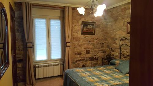 1 dormitorio con cama y pared de piedra en Casa Nunes, en A Coruña