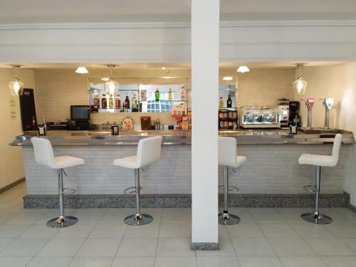 a bar with four white bar stools in a restaurant at Hotel costa mar in Sanxenxo