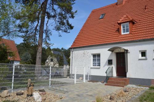 une maison blanche avec un toit rouge et une clôture dans l'établissement FH Hannahliese_WEND, à Karlshagen