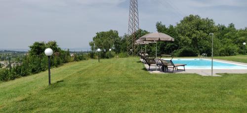 a swimming pool with chairs and an umbrella next to a field at Poggio di Pastrengo in Pastrengo