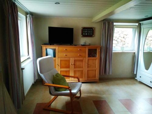 a living room with a chair and a television at Fahrradpension am Weg nach Kopenhagen in Fürstenberg-Havel