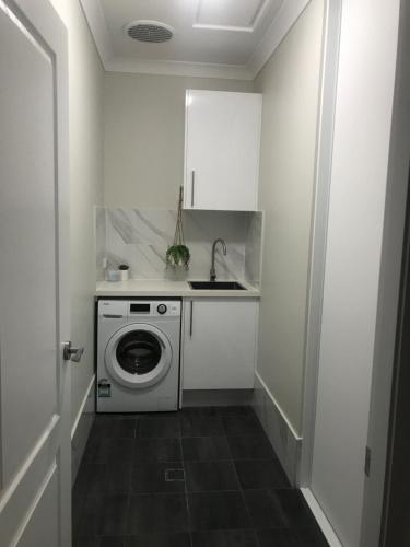 uma pequena cozinha com uma máquina de lavar roupa e um lavatório em Luxury 2br home with King, 5 star private & close em Bathurst