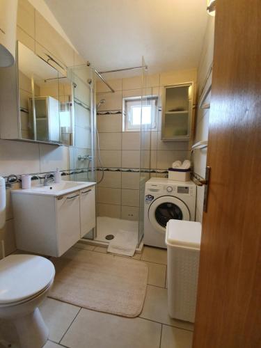 un bagno con un lavandino del water e una lavatrice di Apartment Marta a Pag
