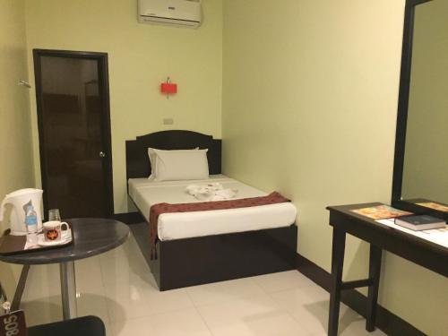 a small bedroom with a bed and a table at Hollywood Suites in General Santos