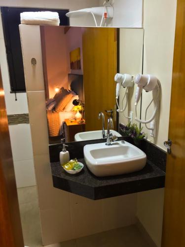 a bathroom with a sink and a mirror at Pousada Divina Minas in André Resende
