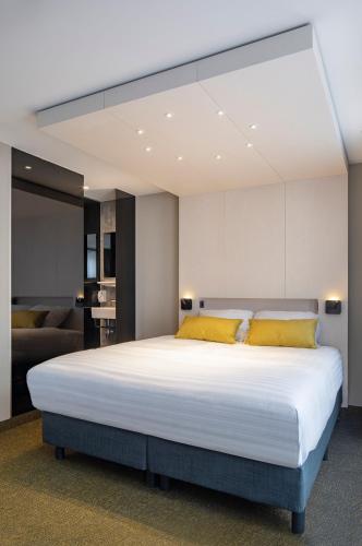 a bedroom with a large white bed with yellow pillows at Cityview Hotel in Amsterdam