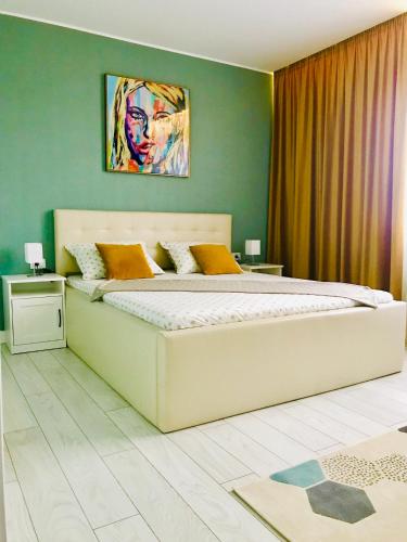 a bedroom with a large bed with a painting on the wall at DarNiDa Luxury Apartment in Mamaia Sat/Năvodari