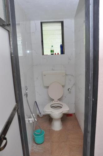 een badkamer met een wit toilet en een raam bij Suvarna Holiday Home in Kashid