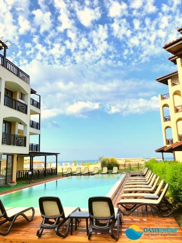a swimming pool with chaise lounge chairs next to a building at Oasis Del Sol - Front Beach in Lozenets