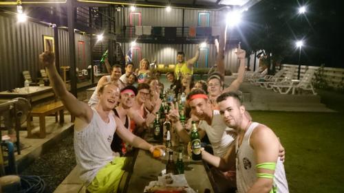 a group of people sitting at a table with beers at Na-tub Hostel in Ban Tai