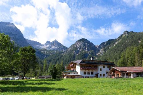 a building in a field with mountains in the background at Alpengasthof Gern Alm in Pertisau