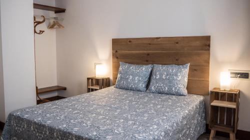 a bedroom with a bed with a wooden headboard and two lamps at Apartamento El Teatro in Écija