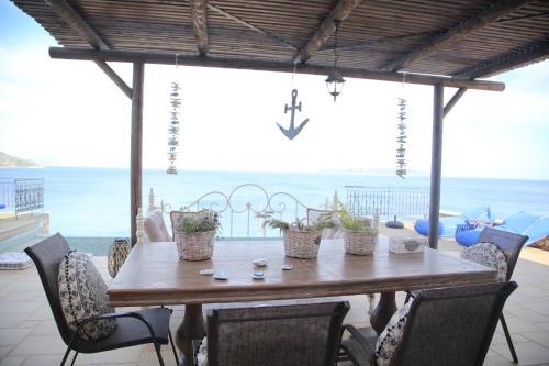 a wooden table and chairs with a view of the ocean at Villa LeSunLuka Lefkada in Vasiliki