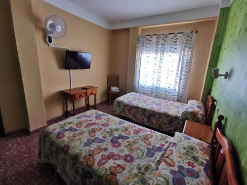 a hotel room with two beds and a window at Hostal Doña Carmen in Ronda