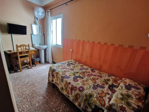 a bedroom with a bed and a desk and a window at Hostal Doña Carmen in Ronda