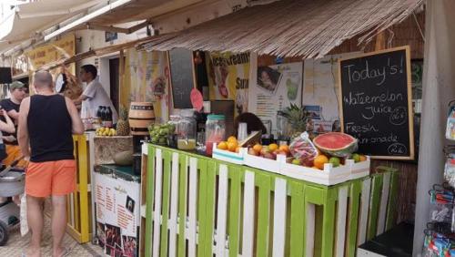 a group of people standing around a fruit stand at Wish & Stay in Albufeira