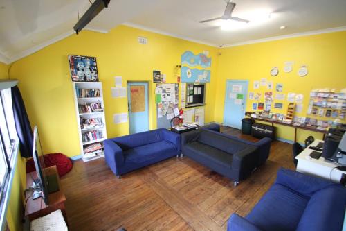 a living room with blue couches and yellow walls at Wander Inn Bunbury in Bunbury