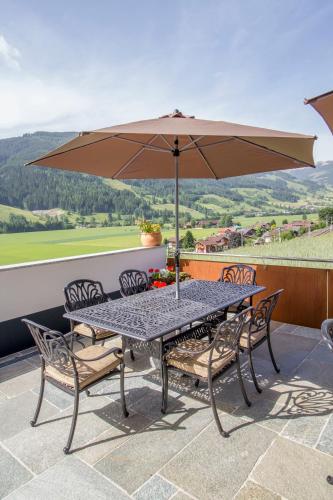 a table and chairs with an umbrella on a patio at Pension Tannenhof in Leogang