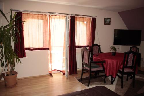 a living room with a red table and chairs at Fox Apartmanok in Hévíz